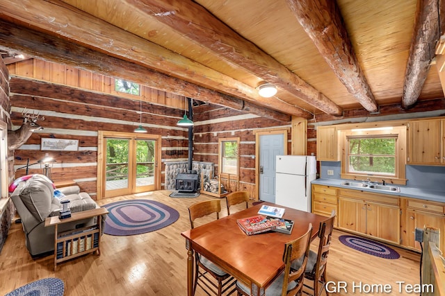 8607 S Ferris Ave, Newaygo, MI 49337 - dining space with a wood stove, light wood finished floors, plenty of natural light, a wooden ceiling with exposed beams, and wood walls