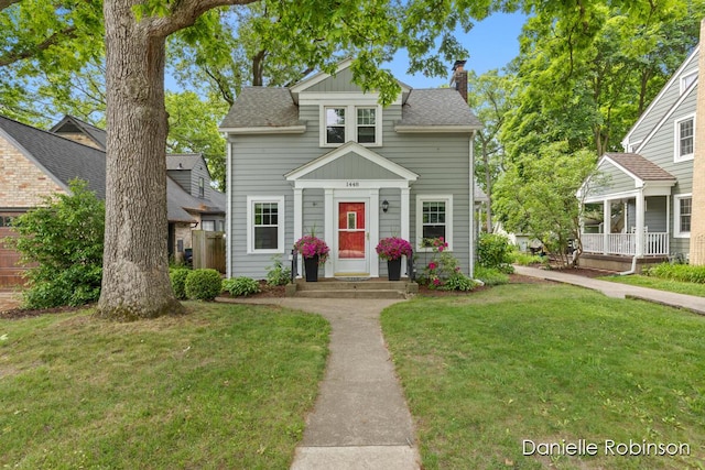 1448 Hall St SE, Grand Rapids, MI 49506 - view of front of house featuring a front lawn, a chimney, roof with shingles, and board and batten siding