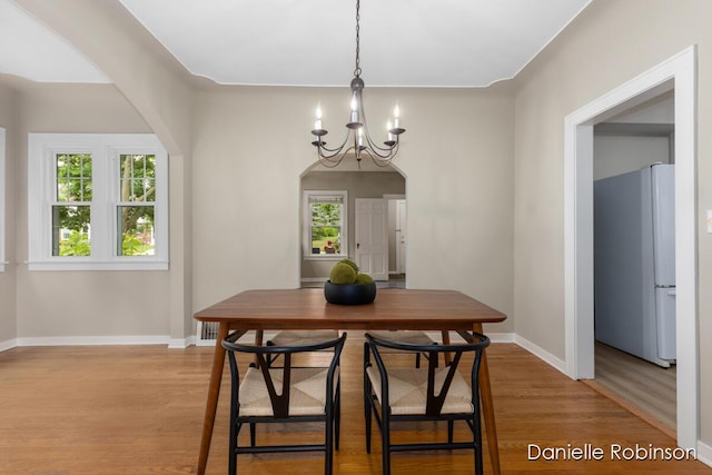 1448 Hall St SE, Grand Rapids, MI 49506 - dining room featuring light wood-style flooring, a chandelier, and arched walkways