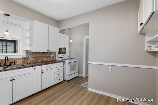 1448 Hall St SE, Grand Rapids, MI 49506 - kitchen featuring white gas range oven, open shelves, white cabinets, decorative backsplash, and light wood-style flooring