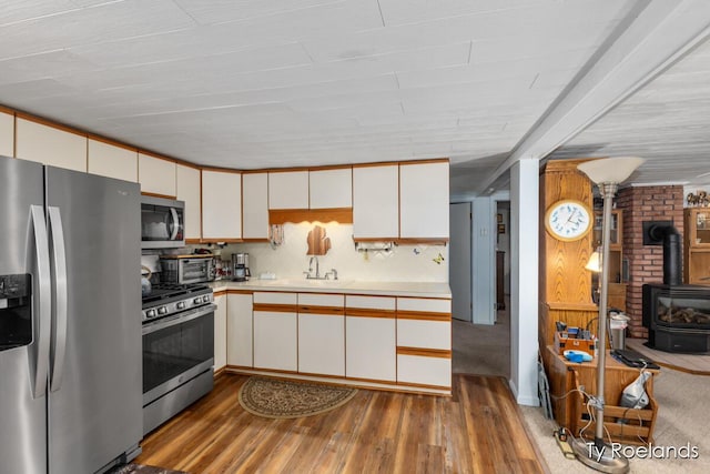 10667 220th Ave, Big Rapids, MI 49307 - kitchen with appliances with stainless steel finishes, a wood stove, light countertops, and wood finished floors
