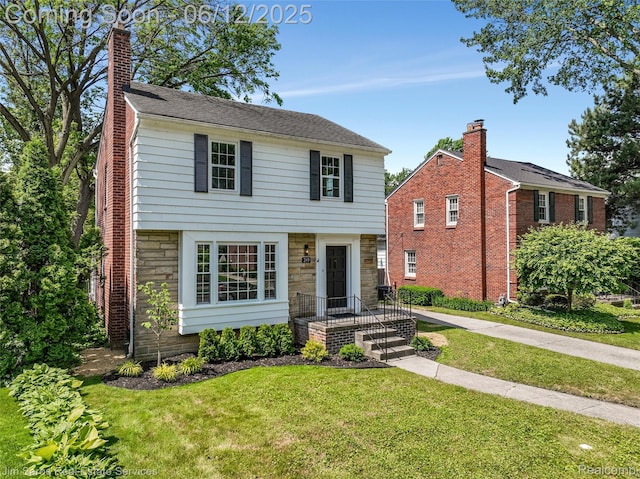 249 Ridgemont Rd, Grosse Pointe, MI 48236 - colonial home with stone siding, a front yard, and a chimney
