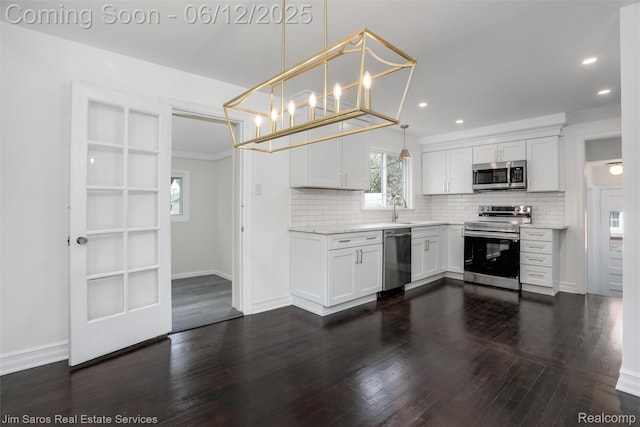 249 Ridgemont Rd, Grosse Pointe, MI 48236 - kitchen featuring appliances with stainless steel finishes, backsplash, white cabinets, dark wood-style flooring, and decorative light fixtures