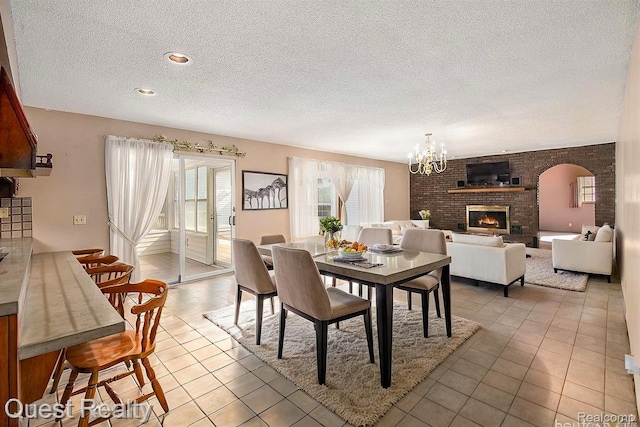 14050 Shannon Dr, Cement City, MI 49233 - dining space with a textured ceiling, a fireplace, tile patterned flooring, and a chandelier