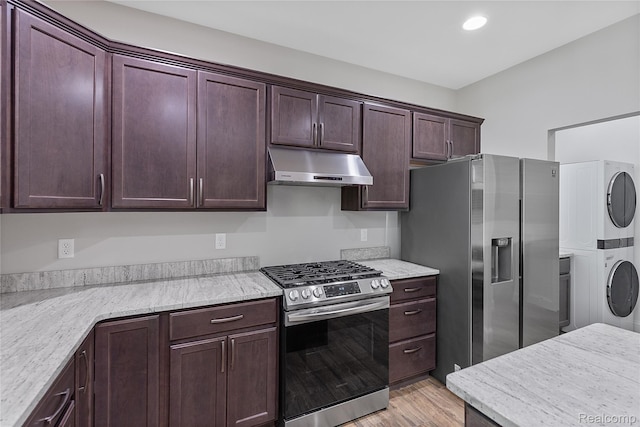47467 Bayside Cir W, Chesterfield, MI 48047 - kitchen with stainless steel appliances, under cabinet range hood, estacked washer and dryer, light wood-style flooring, and dark brown cabinetry