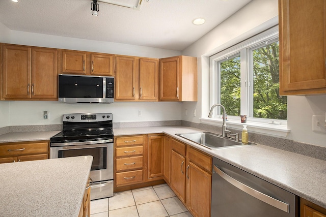5448 Waterfield Ct, Ann Arbor, MI 48108 - kitchen featuring appliances with stainless steel finishes, light countertops, light tile patterned floors, brown cabinetry, and recessed lighting