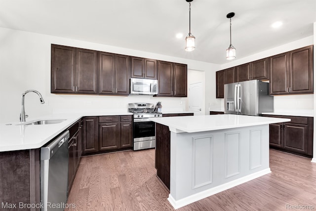 2799 Gallop Way, Saline, MI 48176 - kitchen with stainless steel appliances, light wood-type flooring, dark brown cabinets, light countertops, and a center island