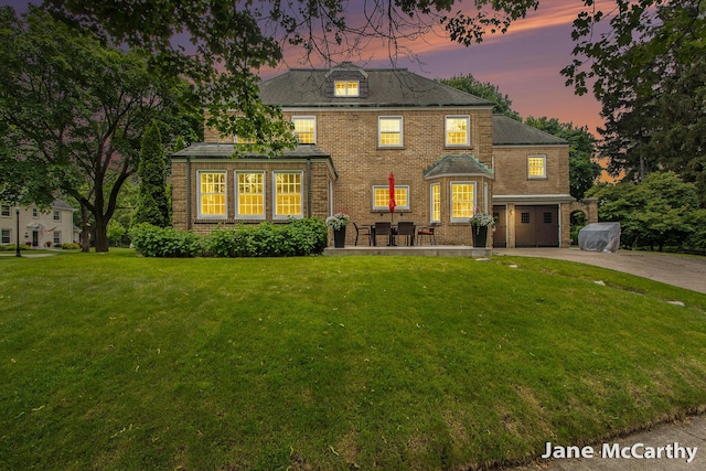 1101 Cadillac Dr SE, Grand Rapids, MI 49506 - back of house at dusk with a yard, brick siding, and concrete driveway