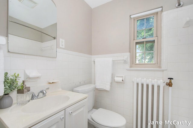 1101 Cadillac Dr SE, Grand Rapids, MI 49506 - bathroom featuring radiator heating unit, tile walls, vanity, and a shower