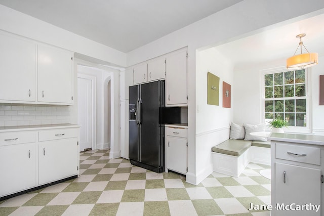 1101 Cadillac Dr SE, Grand Rapids, MI 49506 - kitchen with light flooring, black fridge with ice dispenser, white cabinetry, and light countertops