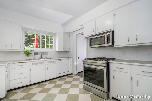 1101 Cadillac Dr SE, Grand Rapids, MI 49506 - kitchen with stainless steel appliances, light floors, light countertops, white cabinetry, and backsplash