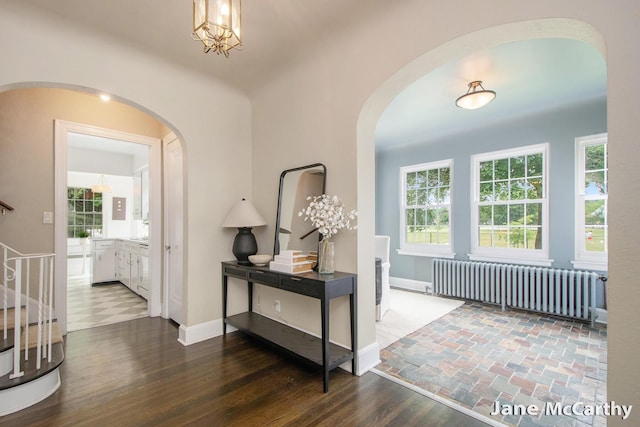 1101 Cadillac Dr SE, Grand Rapids, MI 49506 - corridor with radiator heating unit, arched walkways, stairway, and wood finished floors