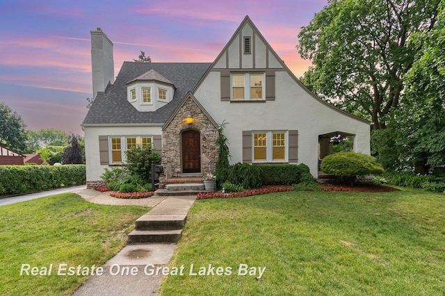 34 E Hannum Blvd, Saginaw, MI 48602 - tudor home featuring stucco siding, stone siding, a chimney, and a yard