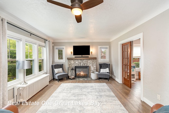 34 E Hannum Blvd, Saginaw, MI 48602 - sitting room featuring radiator, a fireplace, a textured ceiling, a ceiling fan, and wood finished floors