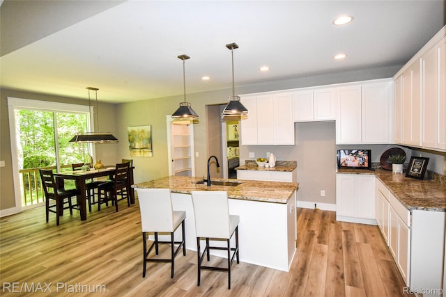 74 Candlelight, Brighton, MI 48114 - kitchen featuring light wood finished floors, an island with sink, white cabinetry, recessed lighting, and stone counters
