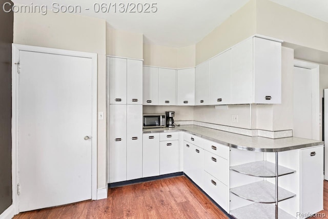 1226 W Genesee St, Lapeer, MI 48446 - kitchen featuring wood finished floors, stainless steel microwave, white cabinets, and light countertops