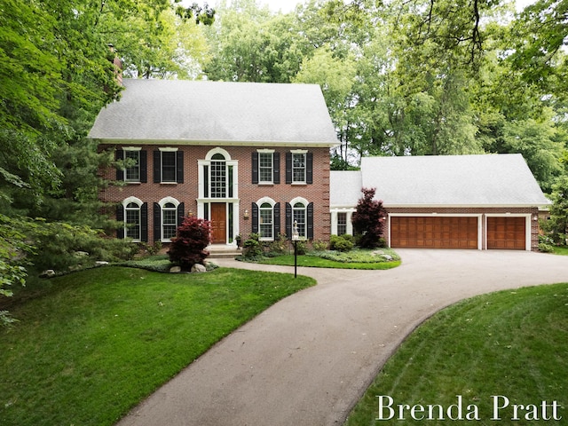 5691 Forest Gln SE, Ada, MI 49301 - colonial-style house with driveway, a front lawn, brick siding, and a garage