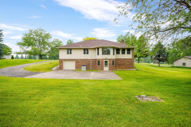 9128 Clover Dr, Milan, MI 48160 - back of house featuring brick siding, a chimney, concrete driveway, a garage, and a yard