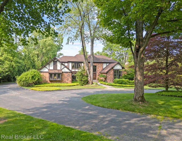 1299 Orchard Ridge Rd, Bloomfield Hills, MI 48304 - tudor house with curved driveway, brick siding, and a front lawn