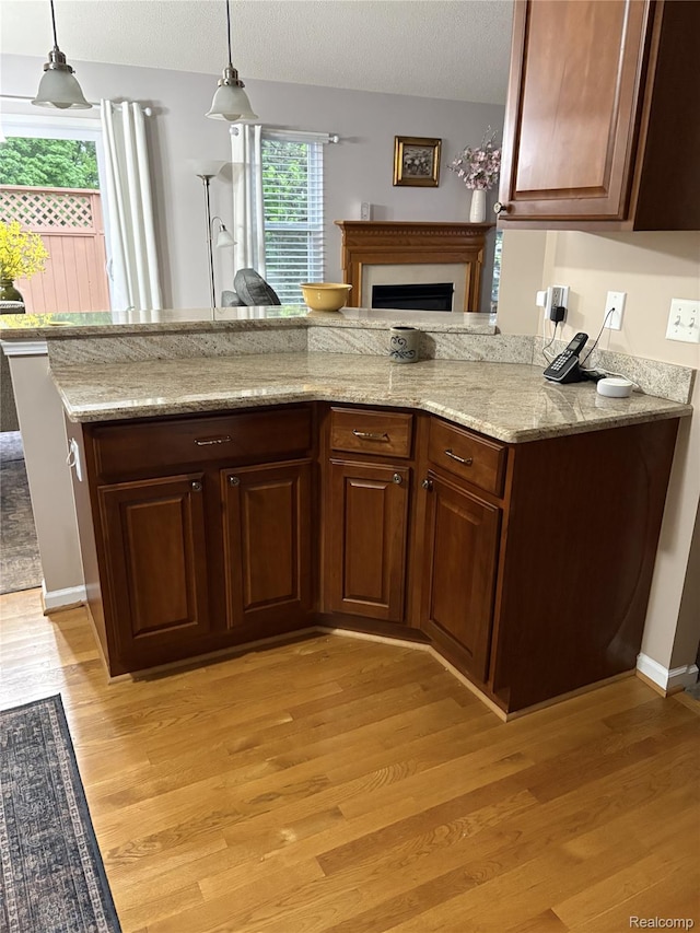11081 Coventry Ct, Taylor, MI 48180 - kitchen with light wood-type flooring, a fireplace, decorative light fixtures, light stone counters, and a textured ceiling