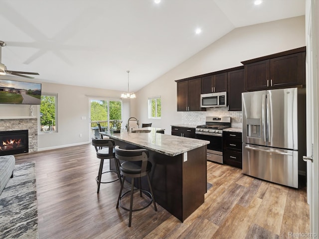 1470 Duncan Dr, Chelsea, MI 48118 - kitchen with appliances with stainless steel finishes, vaulted ceiling, a kitchen breakfast bar, open floor plan, and light wood-style flooring