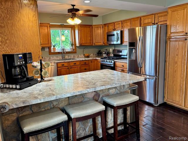 3985 Wadhams Rd, China, MI 48054 - kitchen with appliances with stainless steel finishes, a sink, a peninsula, a ceiling fan, and brown cabinetry