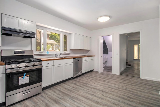 505 Fitch St, Albion, MI 49224 - kitchen with stainless steel appliances, wood counters, under cabinet range hood, light wood-type flooring, and white cabinets