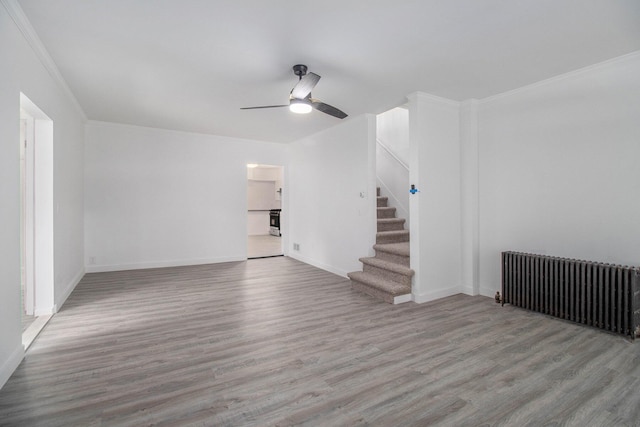 505 Fitch St, Albion, MI 49224 - unfurnished living room with radiator, wood finished floors, ceiling fan, stairway, and crown molding