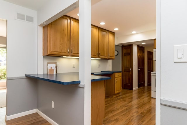 680 Eastlook Dr, Saline, MI 48176 - kitchen featuring dark countertops, wood finished floors, brown cabinets, recessed lighting, and a peninsula