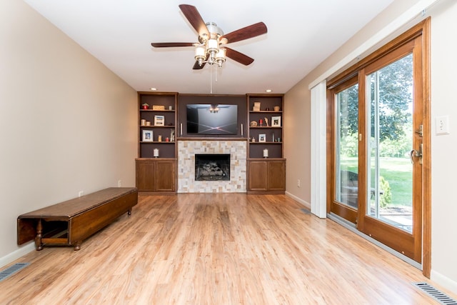 680 Eastlook Dr, Saline, MI 48176 - unfurnished living room featuring wood finished floors, a ceiling fan, a fireplace, and built in shelves