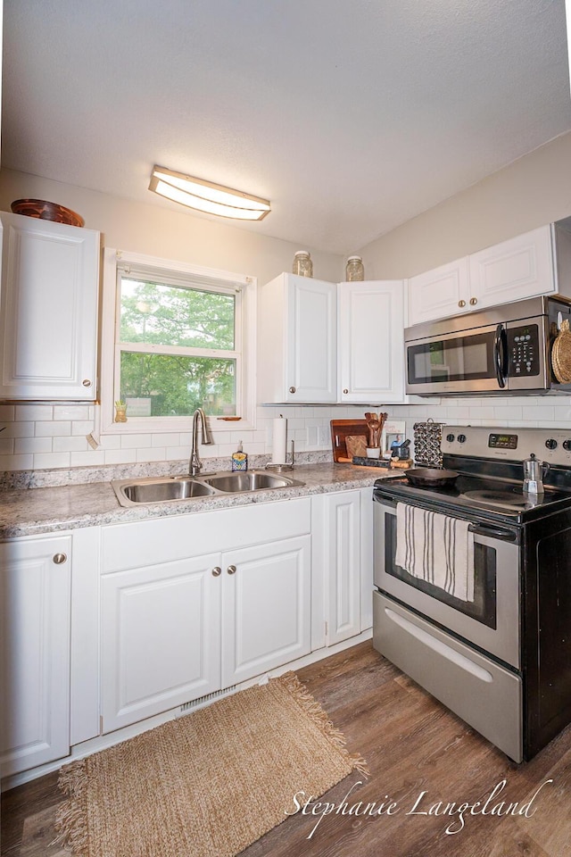 348 Yuba St, Muskegon, MI 49442 - kitchen with appliances with stainless steel finishes, backsplash, white cabinetry, and wood finished floors
