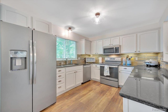 737 Camilla Blvd, Lake Orion, MI 48362 - kitchen featuring appliances with stainless steel finishes, white cabinets, decorative backsplash, dark stone countertops, and light wood-style floors