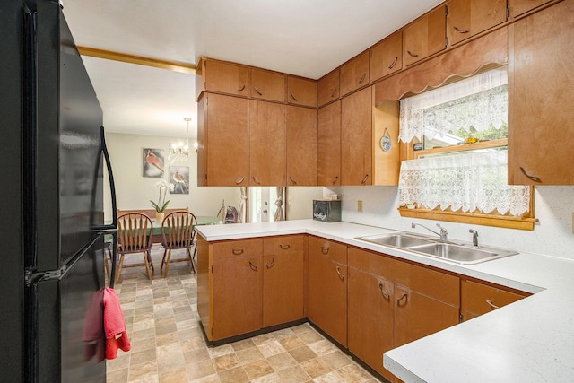 6361 Plainfield Ave, Kalamazoo, MI 49048 - kitchen featuring freestanding refrigerator, light countertops, a peninsula, and a chandelier