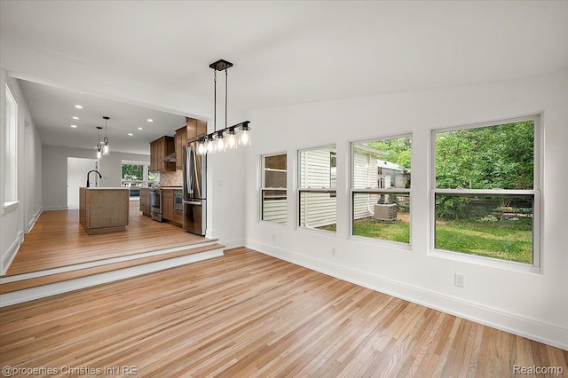15589 Kirkshire Ave, Beverly Hills, MI 48025 - kitchen featuring light countertops, light wood-style floors, a kitchen island with sink, open floor plan, and pendant lighting