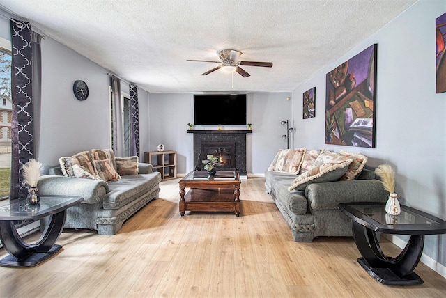 6236 Arbutus, Idlewild, MI 49642 - living area featuring ceiling fan, hardwood / wood-style flooring, a textured ceiling, a glass covered fireplace, and healthy amount of natural light