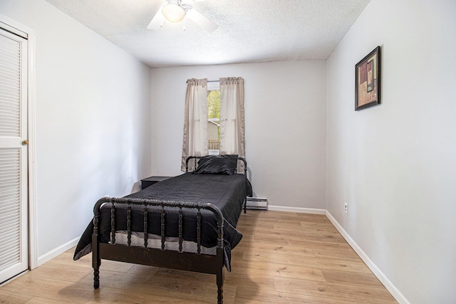 6236 Arbutus, Idlewild, MI 49642 - bedroom featuring baseboard heating, light wood-style floors, a textured ceiling, and ceiling fan