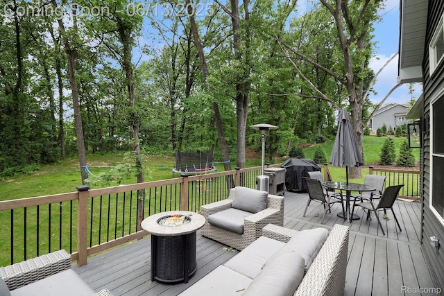5950 Mountain Top Dr, Brighton, MI 48116 - deck with a trampoline, a fire pit, outdoor dining space, a lawn, and grilling area