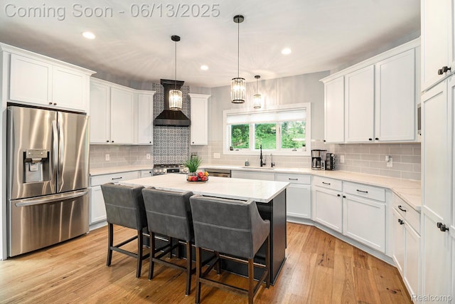 5950 Mountain Top Dr, Brighton, MI 48116 - kitchen featuring stainless steel refrigerator with ice dispenser, wall chimney exhaust hood, white cabinetry, a breakfast bar area, and light wood finished floors