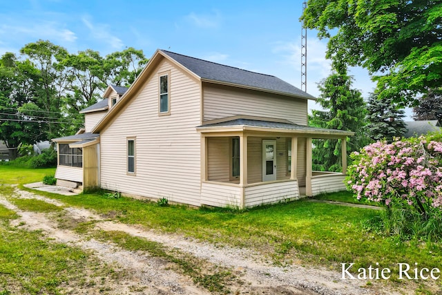 8974 Park St, Montague, MI 49437 - view of home's exterior featuring a sunroom, roof with shingles, a lawn, and covered porch