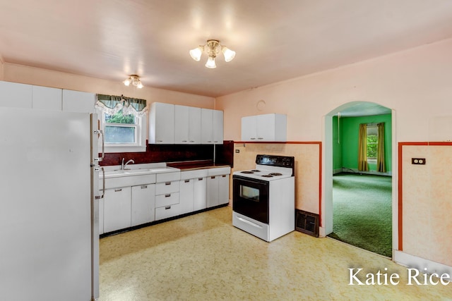 8974 Park St, Montague, MI 49437 - kitchen with freestanding refrigerator, electric range oven, arched walkways, white cabinetry, and decorative backsplash