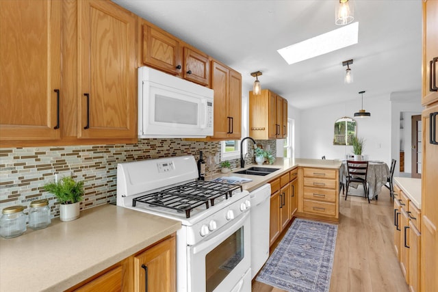6626 Dennison Rd, Plainwell, MI 49080 - kitchen featuring white appliances, a skylight, light wood-style flooring, light countertops, and decorative backsplash