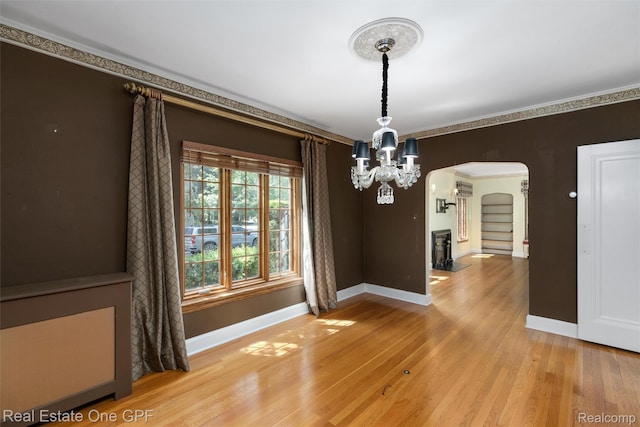 542 Cadieux Rd, Grosse Pointe, MI 48230 - unfurnished dining area featuring arched walkways, light wood finished floors, and a chandelier