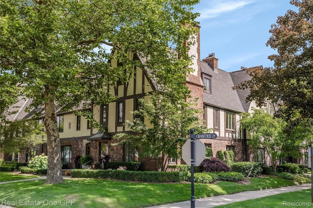 542 Cadieux Rd, Grosse Pointe, MI 48230 - view of front of house with brick siding, stucco siding, a front yard, and a chimney