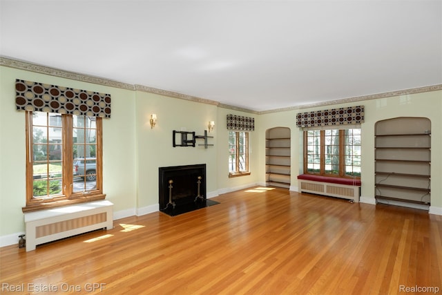 542 Cadieux Rd, Grosse Pointe, MI 48230 - unfurnished living room with radiator, arched walkways, light wood-style flooring, and plenty of natural light