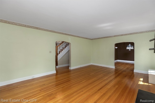 542 Cadieux Rd, Grosse Pointe, MI 48230 - empty room with arched walkways, a chandelier, wood finished floors, stairs, and crown molding
