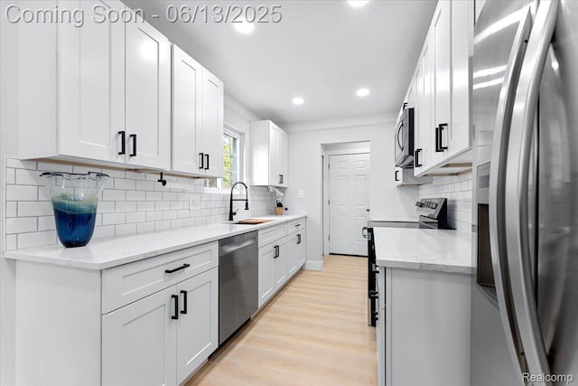 35245 Wick Rd, Romulus, MI 48174 - kitchen with appliances with stainless steel finishes, light wood-type flooring, tasteful backsplash, white cabinetry, and recessed lighting