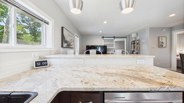 1204 Witham Rd, Muskegon, MI 49445 - kitchen with plenty of natural light, light stone countertops, a barn door, and recessed lighting