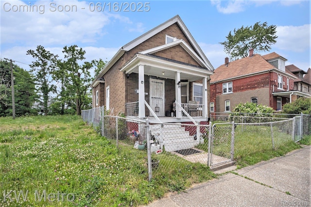 3620 Holborn St, Detroit, MI 48211 - shotgun-style home featuring a gate, brick siding, covered porch, and a fenced front yard