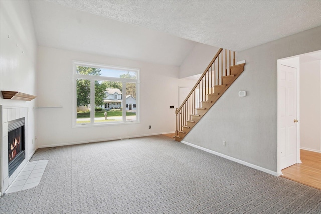 4540 Spinnaker Ln, Pleasant Lake, MI 49272 - unfurnished living room with stairs, a tiled fireplace, carpet flooring, a textured ceiling, and vaulted ceiling