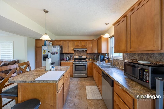 1591 Lillyview Ct SW, Wyoming, MI 49509 - kitchen with stainless steel appliances, backsplash, under cabinet range hood, brown cabinets, and a textured ceiling